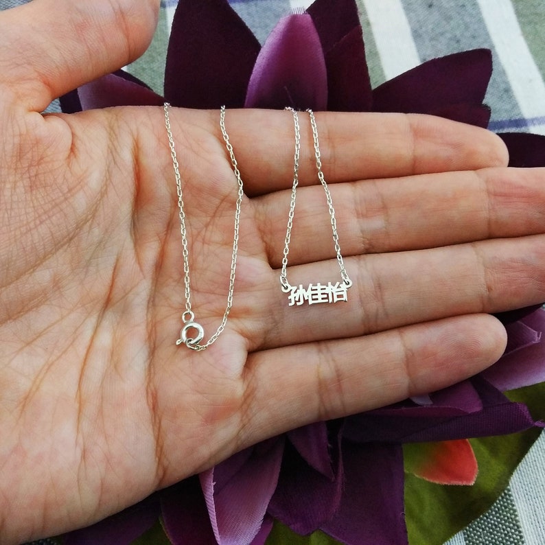 May include: A silver chain necklace with a pendant that says "珍惜" in Chinese characters.