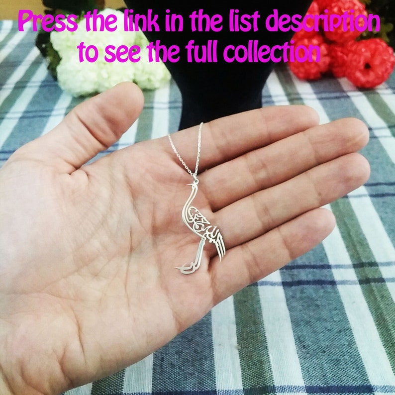 May include: A silver necklace with a delicate pendant shaped like a bird. The bird is made of intricate, openwork design and features Arabic calligraphy.
