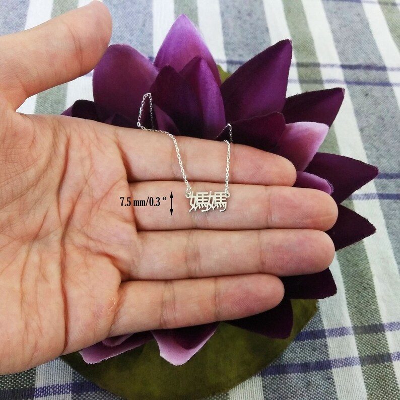 May include: A silver necklace with a delicate chain and a pendant featuring the Chinese characters for "mother" in a 7.5 mm / 0.3 inch font.