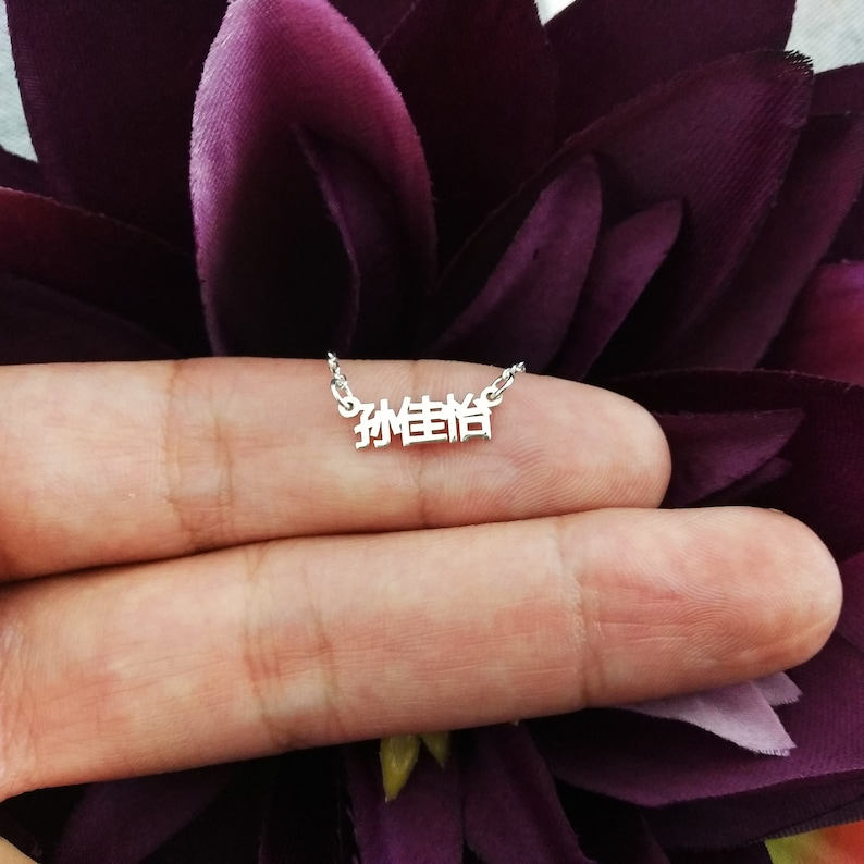 May include: Silver necklace with a delicate chain and a pendant featuring the Chinese characters "珍惜" which translates to "cherish".