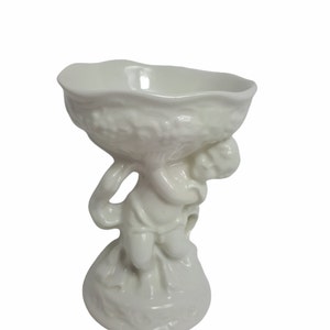 Peut inclure: Bol en céramique blanche tenu par une figure de chérubin. Le chérubin est debout sur un piédestal.
