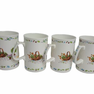 May include: Set of four white ceramic mugs with a floral design and a basket of flowers. Each mug has a handle.