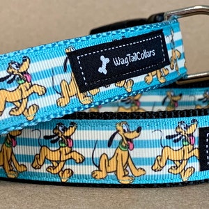 Puede incluir: Dos collares para perros con un fondo a rayas azul y blanco con una imagen de dibujos animados de Pluto. Los collares están hechos por Wag Tail Collars.