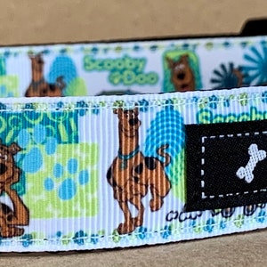 Peut inclure: Collier pour chien blanc avec un imprimé de dessin animé Scooby Doo représentant Scooby et Shaggy. Le collier a une boucle noire et un anneau en D argenté. Le collier est étiqueté "WagTailCollars".
