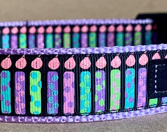 May include: Purple dog collar with a black and white birthday candle pattern. The collar has a silver D-ring and a black label that says "WagTailCollars".