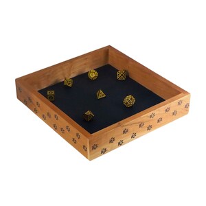 May include: A wooden dice tray with a paw print design. The tray has a black felt lining and is filled with gold dice.