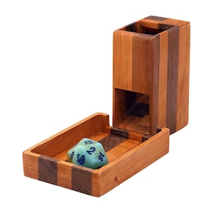 May include: A wooden dice tower and tray set. The tower is made of alternating light and dark wood strips. A light blue die with white numbers rests in the tray. The set is designed for tabletop gaming.