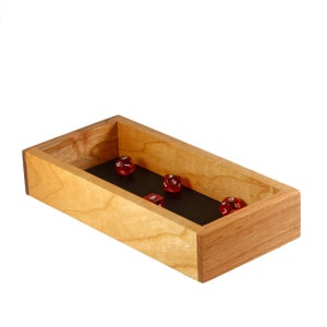 May include: A wooden dice tray with a black felt lining.  Four red dice are inside the tray, showing the numbers 1, 5, 6, and 10.