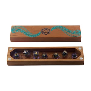 Könnte beinhalten: Eine Holz-Würfelbox mit einem türkisfarbenen Oktopus-Design auf dem Deckel und einer geometrischen Form. Die Box ist geöffnet und zeigt mehrere vielseitige Würfel mit goldenen und violetten Akzenten. Die Würfel sind in einem Holztablett angeordnet.