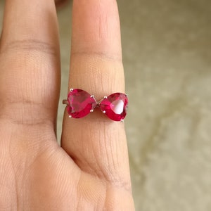 Puede incluir: Un anillo de plata con dos piedras preciosas en forma de corazón rojo.