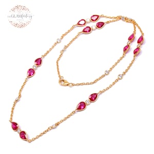 Puede incluir: Un collar de cadena de oro con piedras preciosas rojas en forma de pera y pequeñas piedras redondas transparentes.