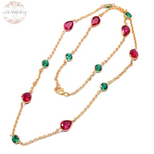 May include: A gold chain necklace with alternating red and green gemstone accents. The necklace features teardrop-shaped red gemstones and round green gemstones.