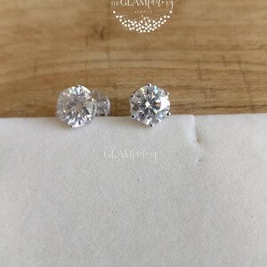 May include: A pair of silver stud earrings with clear round cubic zirconia stones.