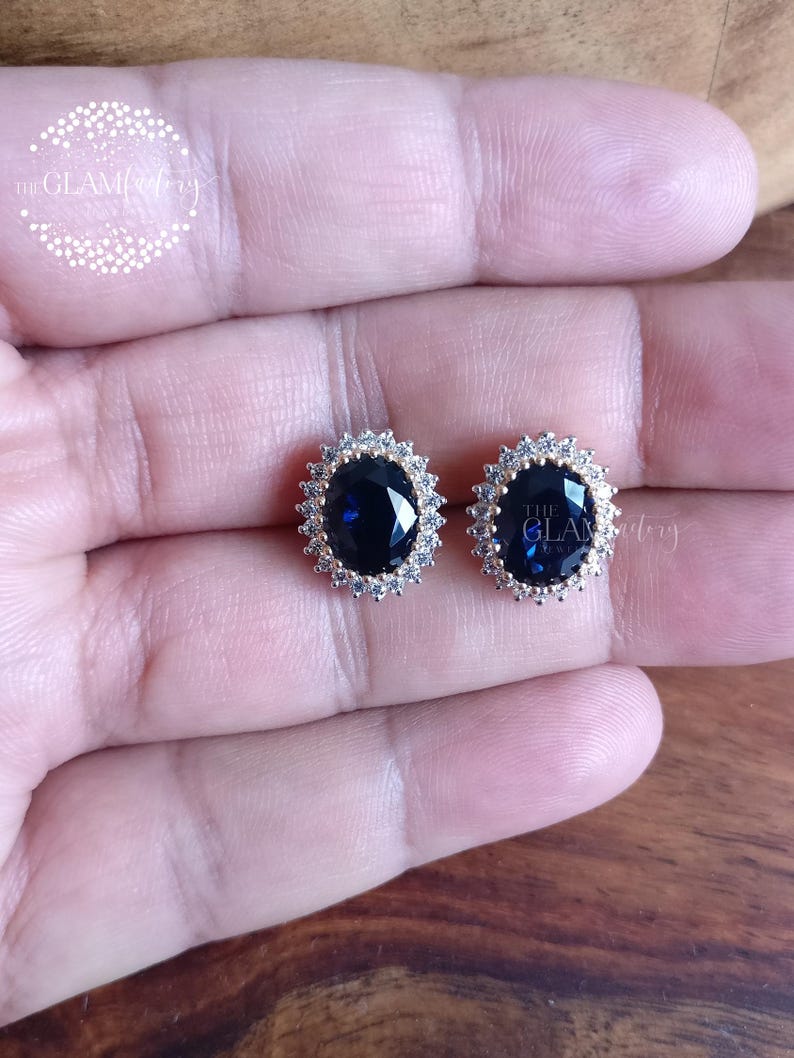 Puede incluir: Un par de pendientes de oro con una gran piedra preciosa azul de forma ovalada rodeada de peque&ntilde;as piedras preciosas blancas.