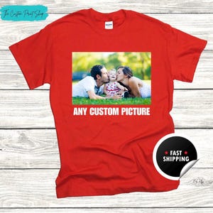 May include: Red t-shirt with a printed image of a family and the text "ANY CUSTOM PICTURE". The shirt also has a "FAST SHIPPING" sticker. The Custom Print Shop logo is visible in the top left corner.