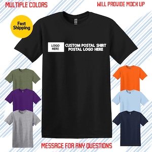 May include: A black t-shirt with the text "LOGO HERE CUSTOM POSTAL SHIRT POSTAL LOGO HERE" in white. The image shows the shirt in multiple colors, including green, purple, gray, orange, light blue, and navy blue. Text at the top says "AVAILABLE IN MULTIPLE COLORS".