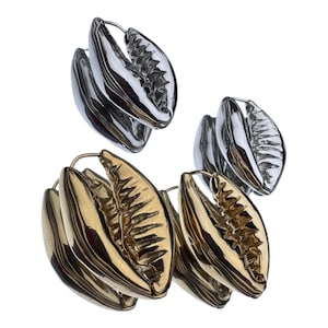 May include: Four pairs of earrings. Two pairs are silver, and two are gold. Each earring has a unique, organic shape with a textured interior. The earrings are designed to be worn on the ear.