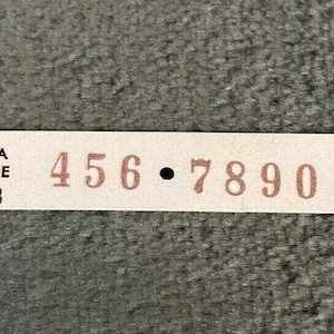 May include: A white label with the text "AREA CODE 123" and the phone number "456-7890" printed in brown.