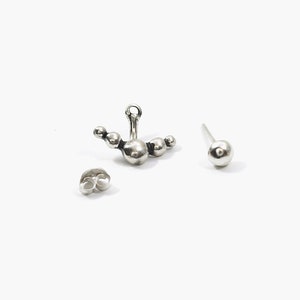 May include: A pair of silver earrings, one with a cluster of five round balls and the other with a single round ball.