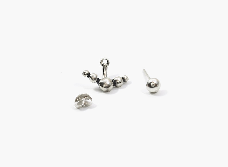 May include: A pair of silver earrings, one with a cluster of five round balls and the other with a single round ball.