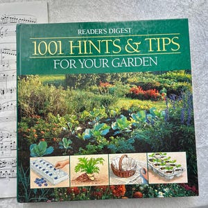 May include: A hardcover book titled "Reader's Digest 1001 Hints & Tips For Your Garden" with a green cover and a garden scene. The book features images of gardening tasks and tools, including seedlings and a woven basket.