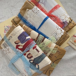 May include: A stack of vintage sewing patterns wrapped in brown paper and tied with blue and white lace. The patterns are labeled with the size "1473" and "Taille C (10,12,14)".