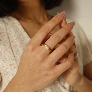 Puede incluir: Un anillo de oro con la palabra "AMOR" grabada. El anillo se lleva en el dedo medio de una mano.