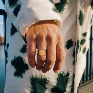 May include: A gold signet ring with a square face.