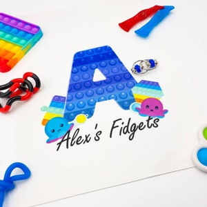 May include: A collection of fidget toys, including a rainbow pop-it, a black and red spring toy, a blue and white pop-it, a blue and white fidget ring, a rainbow fidget spinner, a purple octopus fidget toy, and a green and blue pop-it. The toys are arranged on a white surface with a blue and white letter A and the text "Alex's Fidgets".