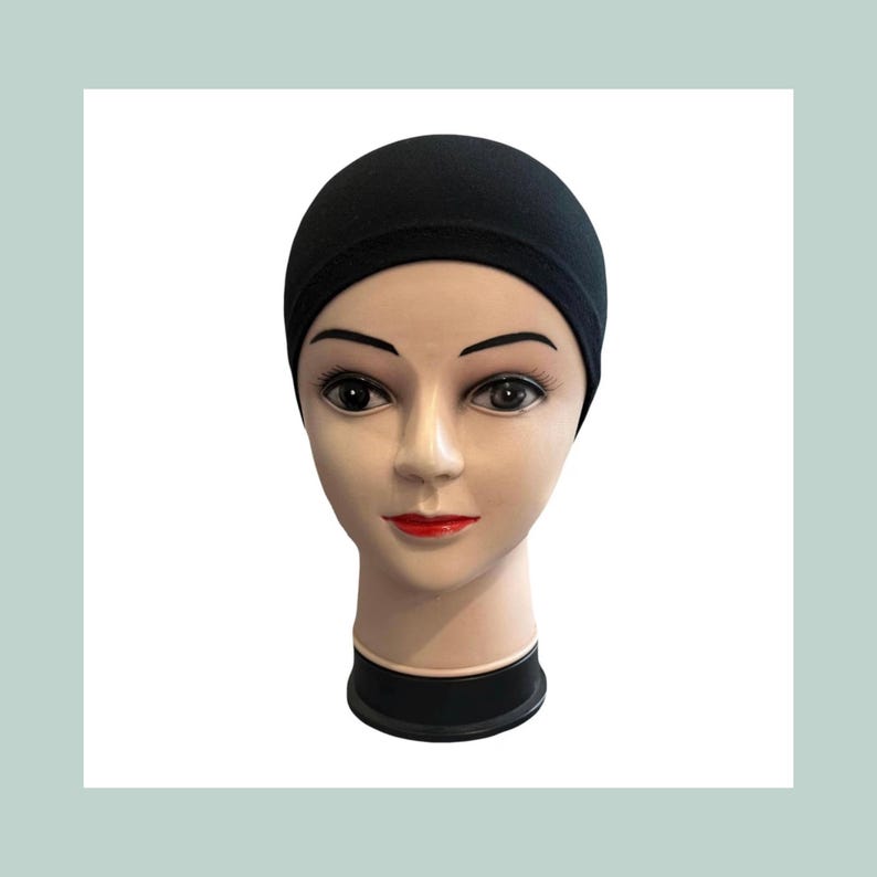 A black cotton jersey cap is displayed on a mannequin head. The cap is smooth and form-fitting. Text on the image reads "Over 30 colours cotton jersey."