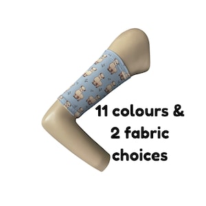 Puede incluir: Una funda de tela azul claro con un patrón repetitivo de pequeñas alpacas marrones y diminutas ramitas verdes, ajustada en un mango beige en forma de L. El texto 11 colours & 2 fabric choices aparece en negro junto al mango.