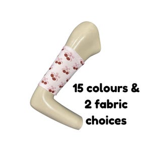 Puede incluir: Una manga de tela rosa claro con un patrón repetitivo de cerezas de color rojo oscuro con tallos y lazos, colocada en un brazo de maniquí beige. El texto 15 colours & 2 fabric choices aparece en negro junto al brazo del maniquí.