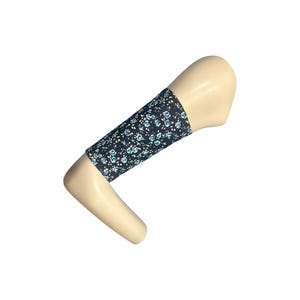 Puede incluir: Una manga de brazo floral negra con un patrón de pequeñas flores azules y blancas. La manga está envuelta alrededor de un brazo de maniquí. La tela parece ser un material ligero.