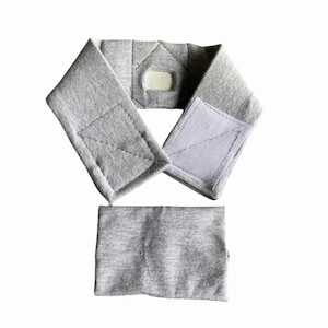 May include: A gray, padded neck brace with a Velcro closure and a separate rectangular pad. The brace is designed to wrap around the neck and is made of a soft, textured fabric. The Velcro closure allows for adjustable sizing.