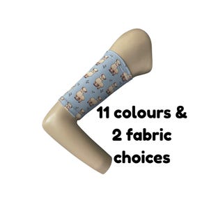 Puede incluir: Una funda de tela azul claro con un patrón repetitivo de pequeñas alpacas marrones y diminutas ramitas verdes, ajustada en un mango beige en forma de L. El texto 11 colours & 2 fabric choices aparece en negro junto al mango.