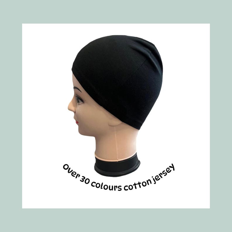 A black cotton jersey cap is displayed on a mannequin head. The cap is smooth and form-fitting. Text on the image reads "Over 30 colours cotton jersey."