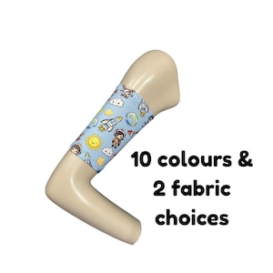 Puede incluir: Una manga de tela azul claro con un patrón repetitivo de astronautas, cohetes, planetas, soles y nubes de dibujos animados. El texto 10 colours & 2 fabric choices aparece en negro junto al brazo de maniquí de color beige.