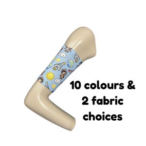 Puede incluir: Una manga de tela azul claro con un patrón repetitivo de astronautas, cohetes, planetas, soles y nubes de dibujos animados. El texto 10 colours & 2 fabric choices aparece en negro junto al brazo de maniquí de color beige.