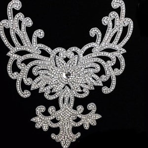 May include: A silver rhinestone applique with a floral design. The applique is perfect for adding a touch of sparkle to clothing, bags, or home decor.