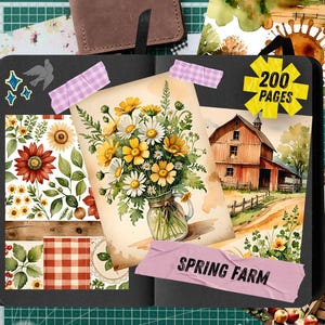 May include: A black journal with watercolor illustrations of a farm scene, sunflowers, and daisies. The journal has 200 pages and includes decorative stickers and washi tape. A brown leather notebook and cutting tools are also visible.