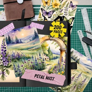 May include: An open black journal with watercolor illustrations of lavender, landscapes, and butterflies. The journal has a sticker that says "200 pages" and a pink label that says "Petal Mist". A brown leather notebook and stationery are in the background.
