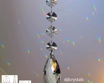 Puede incluir: Un prisma de cristal para lámpara de araña con forma de lágrima y una cadena de cristales octogonales. El prisma está colgado del techo y proyecta arcoíris en la pared. dpcrystals