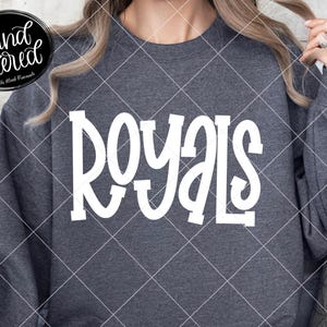 May include: A dark gray sweatshirt with the word "ROYALS" in large white letters across the front. The sweatshirt also has the text "hand lettered" and "The Blank Pineapple" in the image.