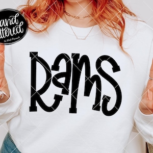 Könnte beinhalten: Weißes Sweatshirt mit dem Wort "RAMS" in großen, fetten, schwarzen Buchstaben auf der Vorderseite. Das Bild enthält auch den Text "hand lettered" in einem schwarzen Kreis und "The Blank Pineapple" mit "SVG PNG EPS" darunter.