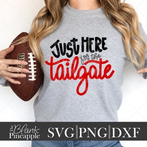 May include: A gray sweatshirt with the text "Just Here for the Tailgate" in black and red. A brown football is held in the left hand. The bottom of the image has the text "The Blank Pineapple SVG PNG DXF".