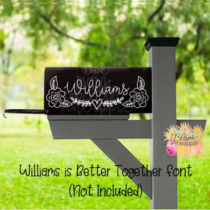 May include: A black mailbox with a white vinyl decal that says "Williams" with a floral design and a heart. The decal is on the front of the mailbox.
