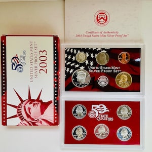 May include: A 2003 United States Mint Silver Proof Set, including a certificate of authenticity and a box with the text "State Quarters". The set contains various coins in protective cases, with the Statue of Liberty on the box.