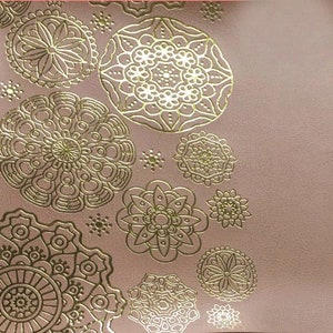 May include: A pink background with a gold pattern of intricate mandalas. The mandalas are in various sizes and are arranged in a random pattern.