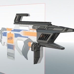 Może przedstawiać: Czarno-szary, 3D-drukowany dodatek do pistoletu Nerf o futurystycznym designie. Dodatek jest zaprojektowany do montażu na pistolecie Nerf i posiada celownik optyczny oraz przedłużkę lufy.