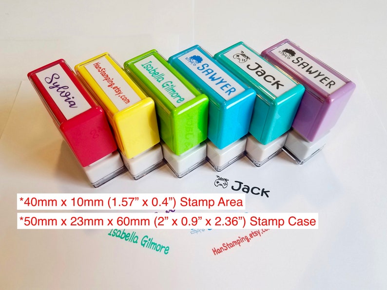 May include: Six rectangular self-inking stamps in red, yellow, green, blue, teal, and purple. Each stamp features a custom name or text label on top. The stamp area is 1.57 inches by 0.4 inches, and the stamp case is 2 inches by 0.9 inches by 2.36 inches.